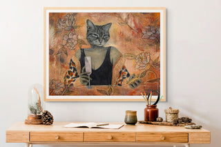 Framed artwork of a cat with floral elements on a wall above a wooden console table.