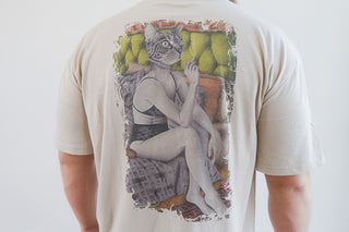 Unisex Welcoming Tuesday T-shirt in sand color by Laura J Stratton, showing a back design with artistic lettering.